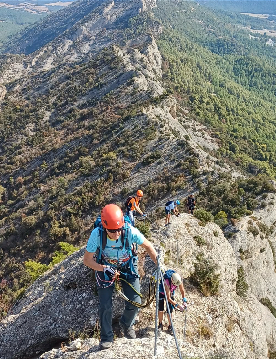 Excursionistes amb casc i corda en una cresta de muntanya
